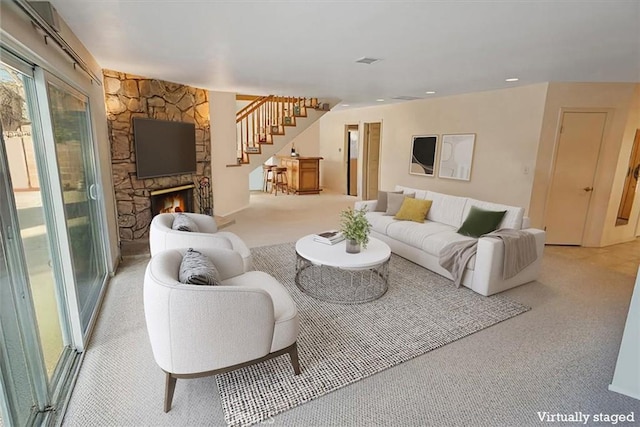 living room with a stone fireplace and light colored carpet