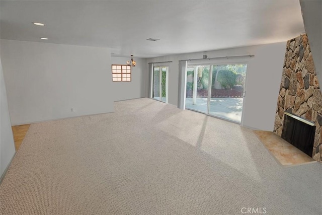 unfurnished living room featuring an inviting chandelier, light colored carpet, and a fireplace