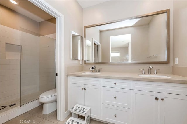 bathroom featuring toilet, vanity, tiled shower, and tile patterned flooring