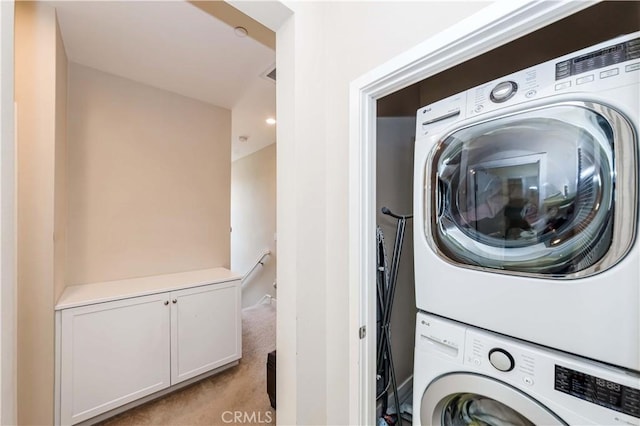 laundry area featuring light carpet and stacked washer and dryer