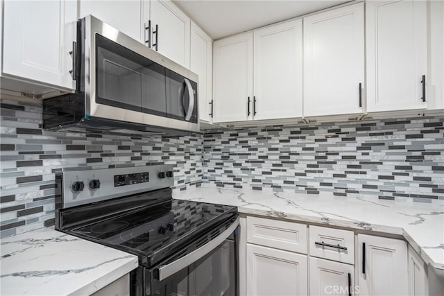 kitchen featuring light stone counters, white cabinets, appliances with stainless steel finishes, and decorative backsplash