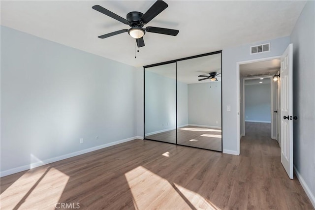 unfurnished bedroom featuring ceiling fan, hardwood / wood-style floors, and a closet