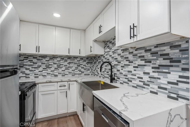 kitchen featuring stainless steel appliances, white cabinets, sink, and tasteful backsplash