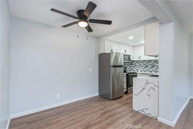 kitchen with white cabinets, ceiling fan, tasteful backsplash, light hardwood / wood-style flooring, and appliances with stainless steel finishes