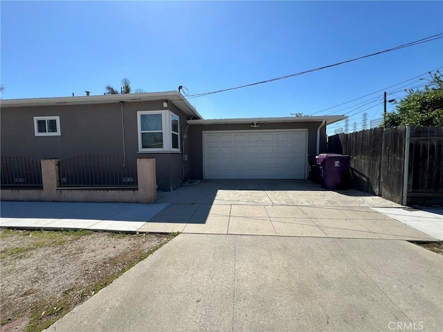 exterior space with fence, a garage, driveway, and stucco siding