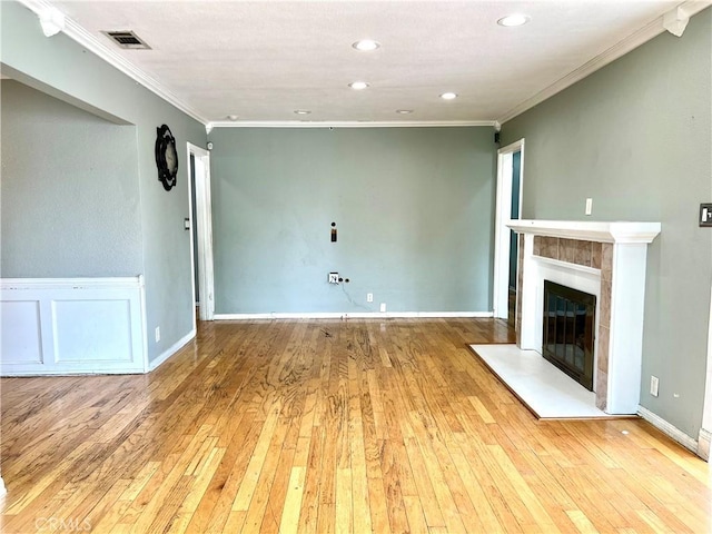 unfurnished living room featuring crown molding, visible vents, light wood-style flooring, and a tile fireplace