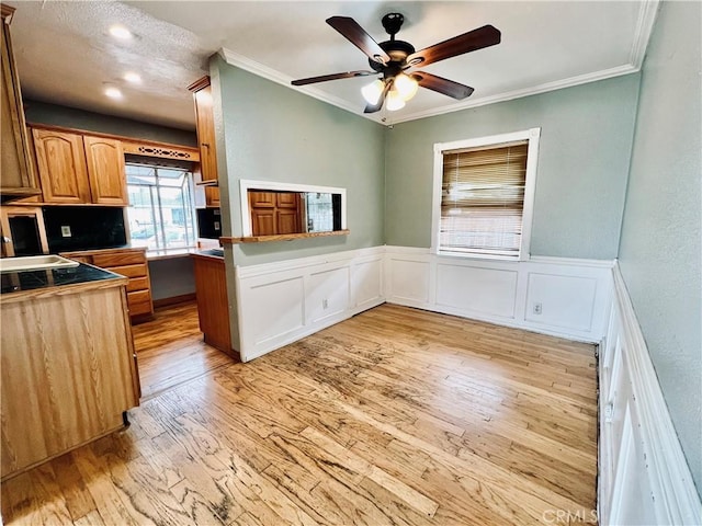 kitchen featuring ornamental molding, ceiling fan, light wood-type flooring, and a peninsula