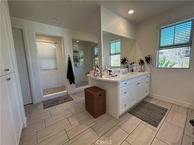 bathroom featuring a healthy amount of sunlight, tiled shower, and vanity