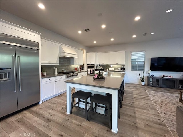 kitchen with stainless steel appliances, white cabinetry, a center island, and custom exhaust hood