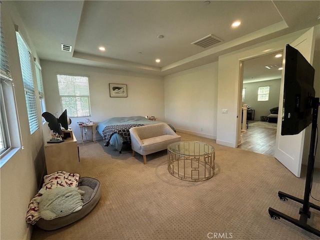 bedroom with a tray ceiling and light colored carpet