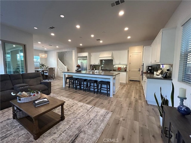 living room with sink, light wood-type flooring, and an inviting chandelier