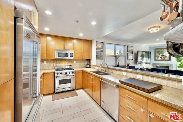 kitchen featuring sink, light tile patterned floors, high quality appliances, light stone countertops, and backsplash