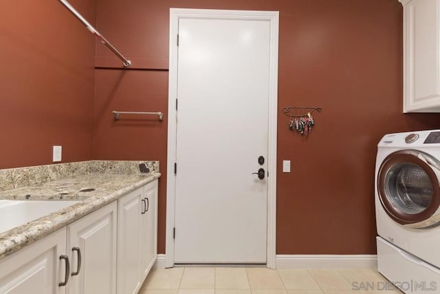 washroom with washer / clothes dryer, cabinets, and light tile patterned floors