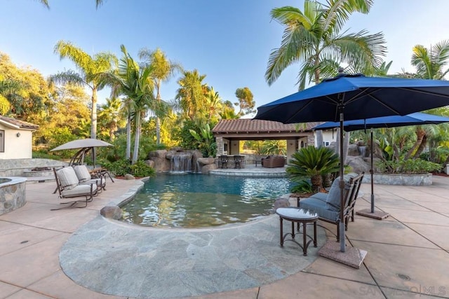 view of swimming pool featuring a patio, pool water feature, and a fire pit