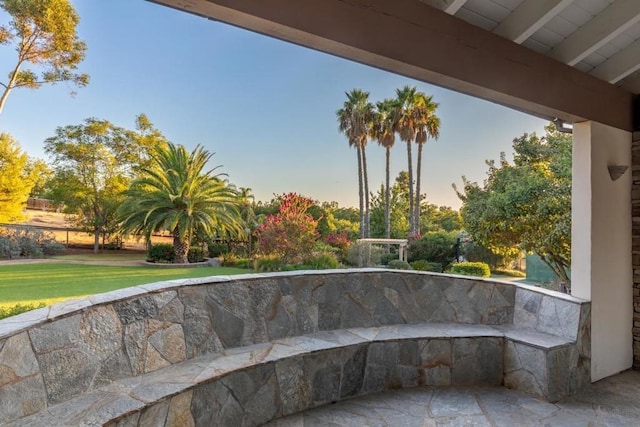 patio terrace at dusk featuring a lawn