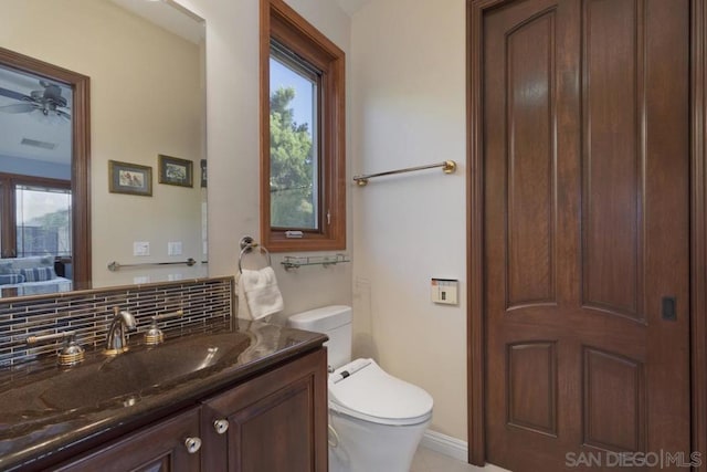 bathroom featuring vanity, toilet, and tasteful backsplash