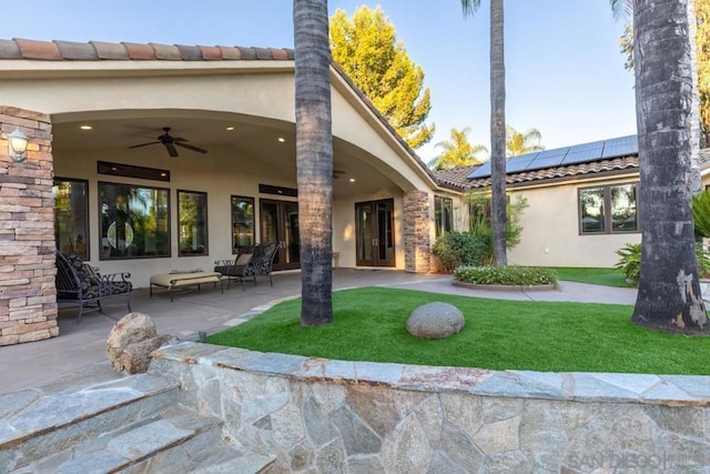 back of house featuring ceiling fan, a patio, a yard, and solar panels