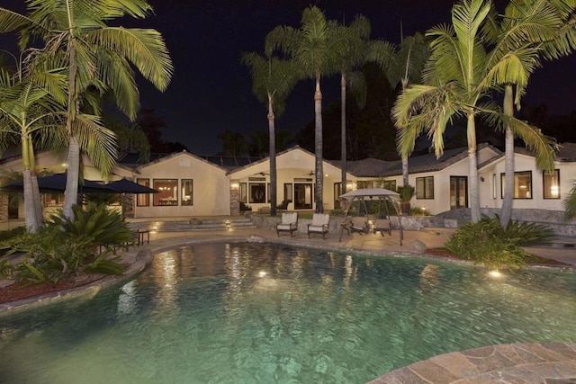 pool at night featuring a patio area