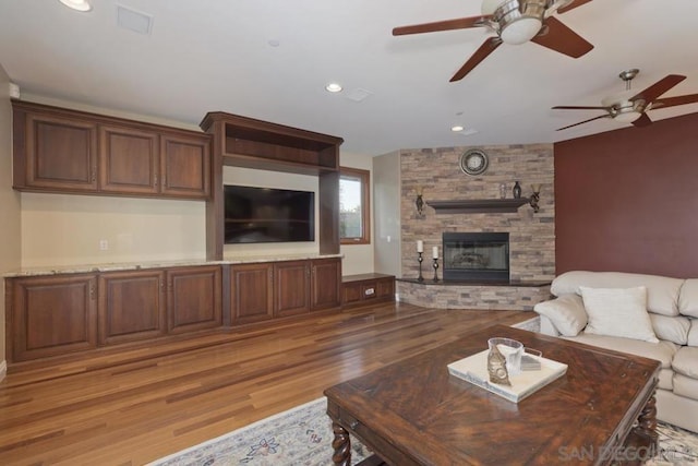 living room featuring a fireplace, hardwood / wood-style floors, and ceiling fan