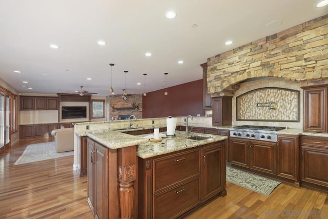 kitchen featuring stainless steel gas stovetop, wood-type flooring, a large island, sink, and pendant lighting