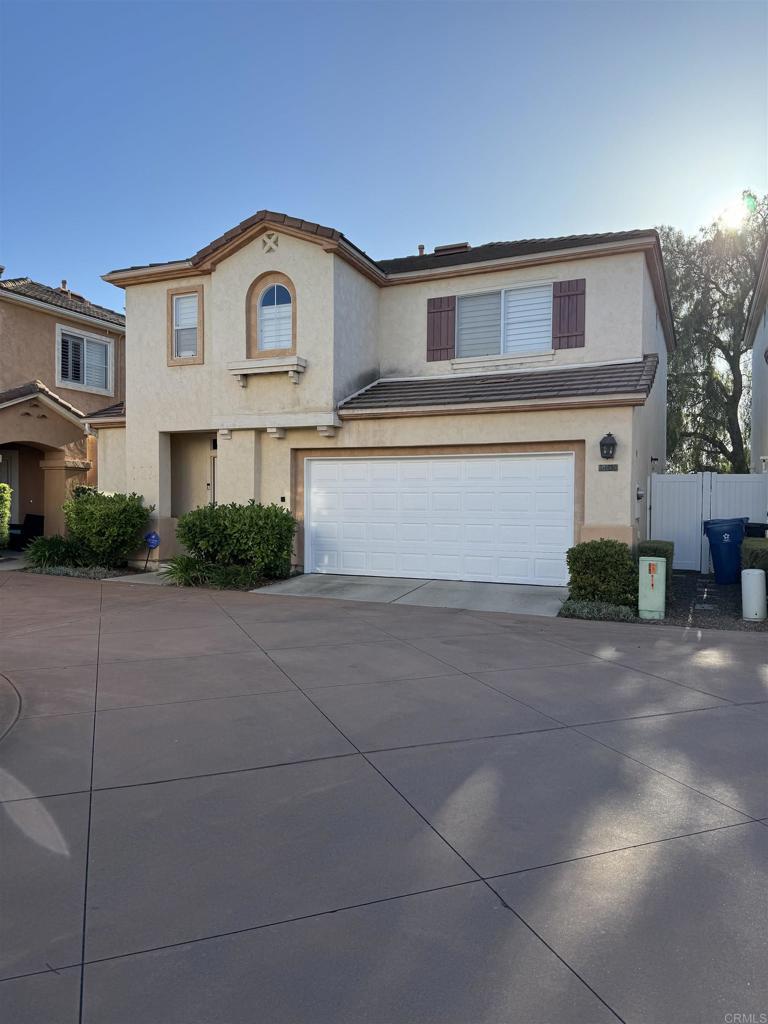 view of front facade with a garage, concrete driveway, a tile roof, and stucco siding