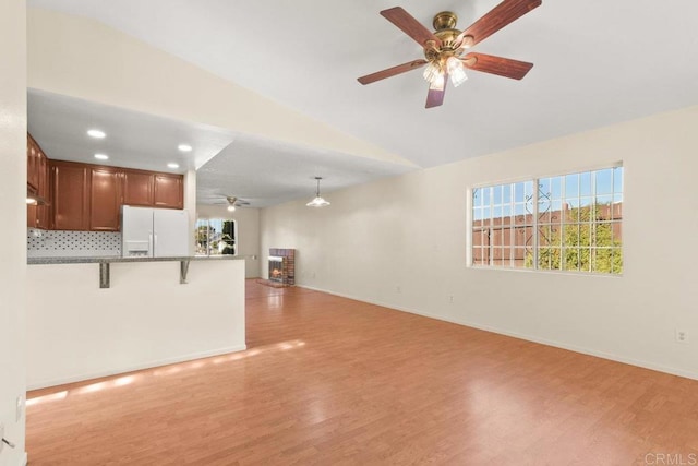 unfurnished living room with a brick fireplace, lofted ceiling, light hardwood / wood-style flooring, and ceiling fan