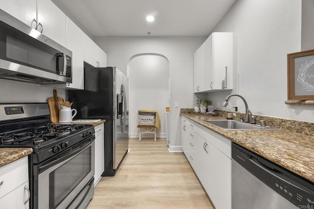 kitchen with white cabinets, appliances with stainless steel finishes, sink, and dark stone countertops