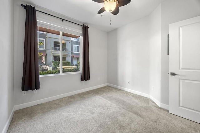 spare room with carpet, baseboards, and a ceiling fan