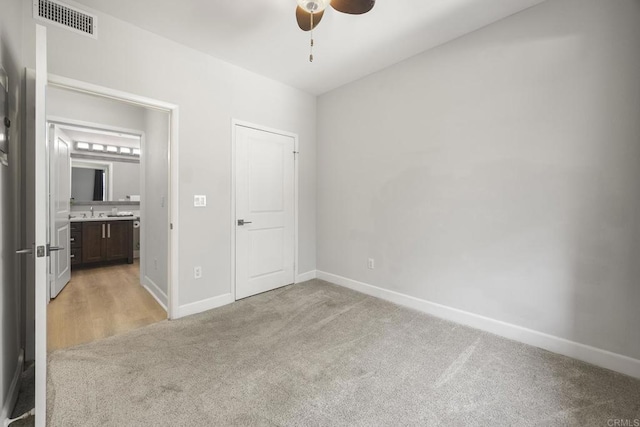 unfurnished bedroom with light carpet, ensuite bathroom, visible vents, and baseboards