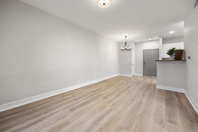 unfurnished room with recessed lighting, visible vents, light wood-style flooring, an inviting chandelier, and baseboards