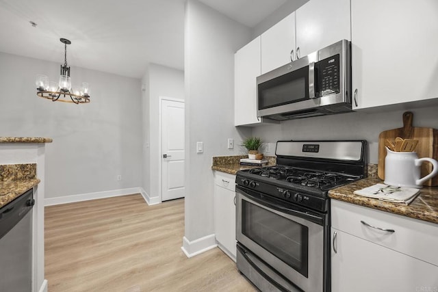 kitchen with dark stone counters, stainless steel appliances, and white cabinets