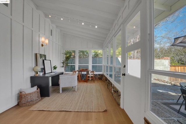 sunroom / solarium featuring vaulted ceiling with beams