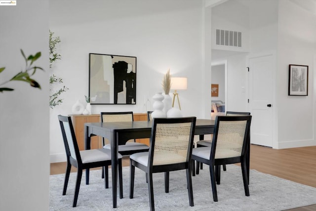 dining area with wood-type flooring and a high ceiling