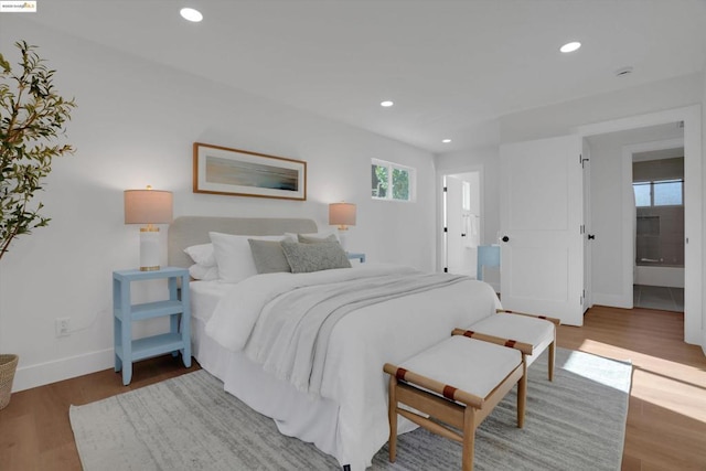 bedroom with ensuite bathroom and hardwood / wood-style floors