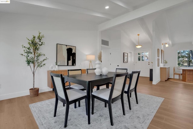 dining room featuring lofted ceiling with beams and light wood-type flooring