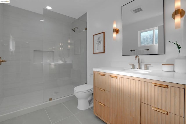 bathroom featuring toilet, vanity, tile patterned flooring, and tiled shower