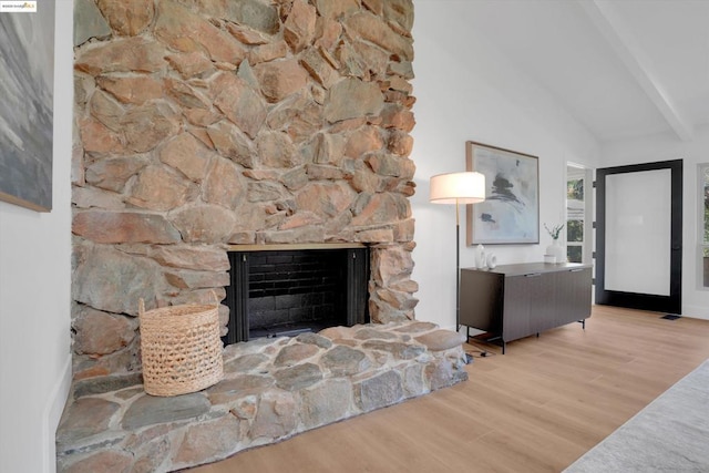 living room featuring light wood-type flooring, lofted ceiling with beams, and a fireplace