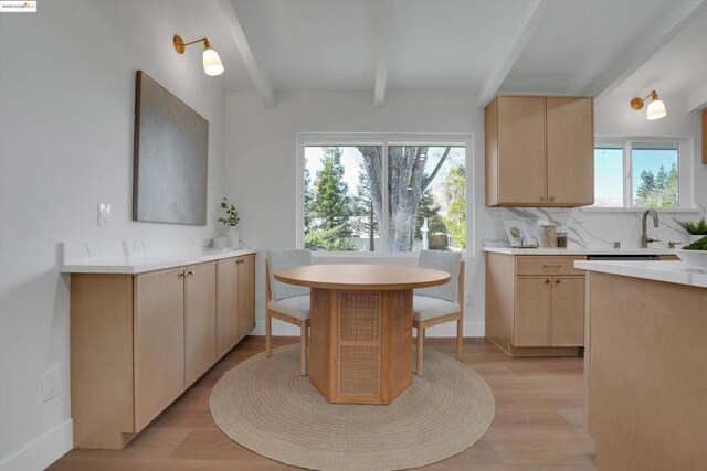 kitchen featuring light brown cabinets, tasteful backsplash, sink, light hardwood / wood-style flooring, and beam ceiling