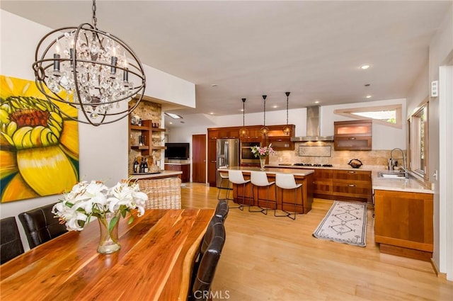 dining area with an inviting chandelier, light hardwood / wood-style floors, and sink