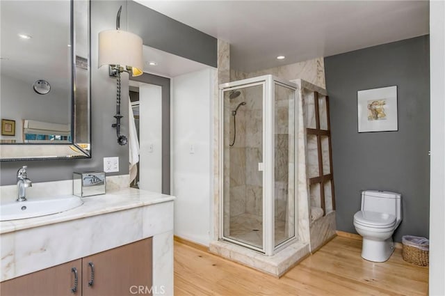 bathroom featuring hardwood / wood-style floors, an enclosed shower, vanity, and toilet