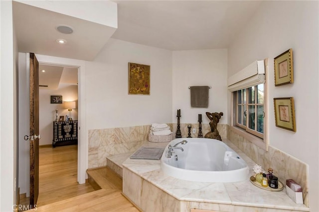 bathroom featuring tiled tub and hardwood / wood-style flooring