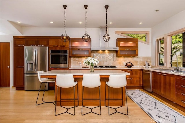 kitchen with a center island, a breakfast bar, sink, hanging light fixtures, and stainless steel appliances