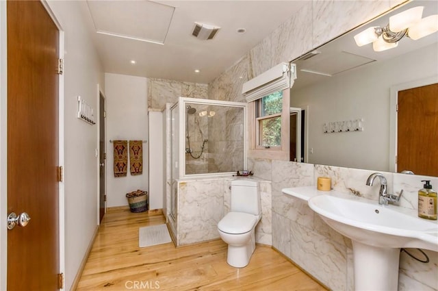 bathroom featuring toilet, a shower with shower door, hardwood / wood-style floors, and sink