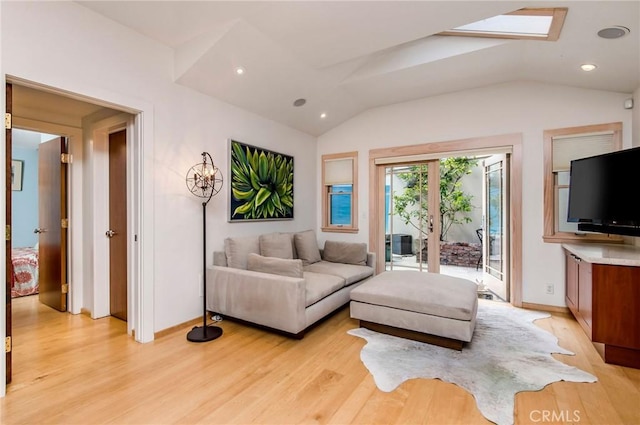 living room featuring light hardwood / wood-style floors and vaulted ceiling with skylight