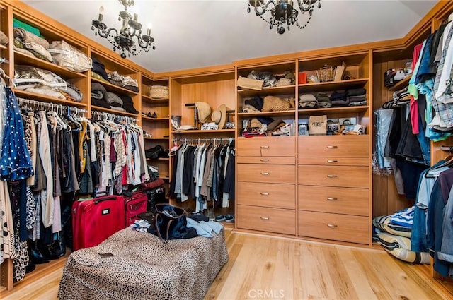 spacious closet with light wood-type flooring and a notable chandelier