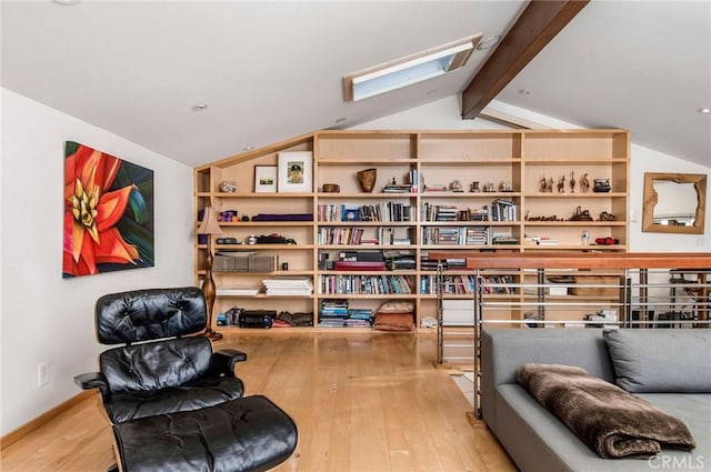 sitting room featuring vaulted ceiling with skylight and hardwood / wood-style flooring