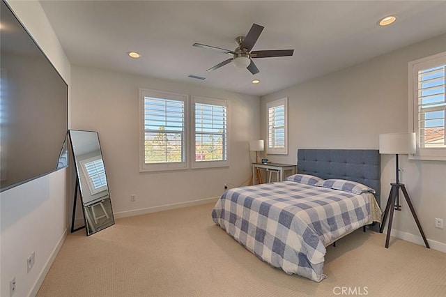 bedroom featuring ceiling fan, light colored carpet, and multiple windows