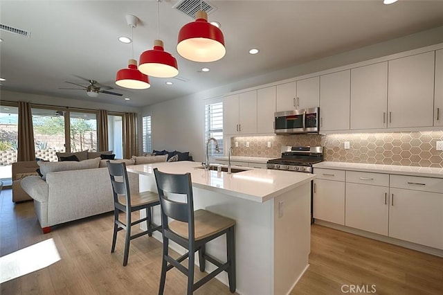 kitchen featuring white cabinetry, stainless steel appliances, sink, a kitchen island with sink, and a breakfast bar