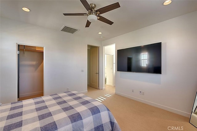 unfurnished bedroom featuring light carpet, ceiling fan, a closet, and a spacious closet