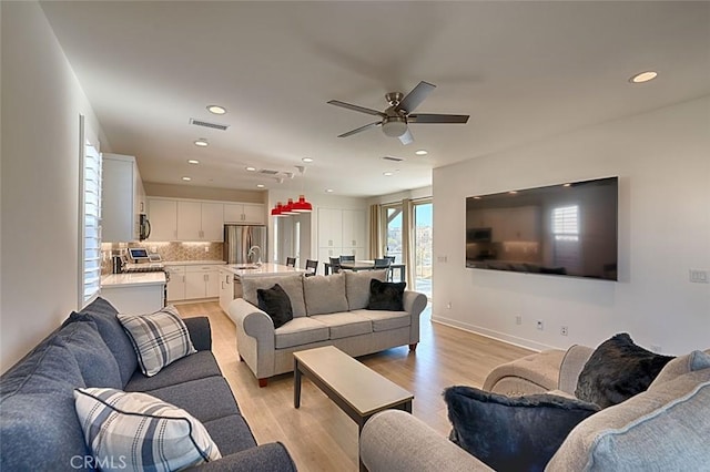 living room with ceiling fan, light hardwood / wood-style flooring, and sink